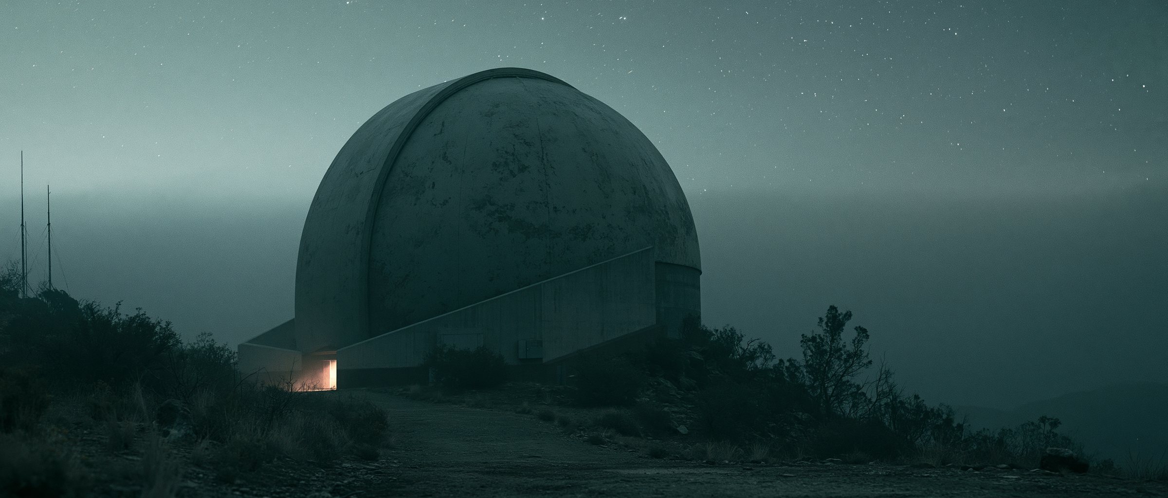 The observatory dome at night under a field of stars, one lit doorway